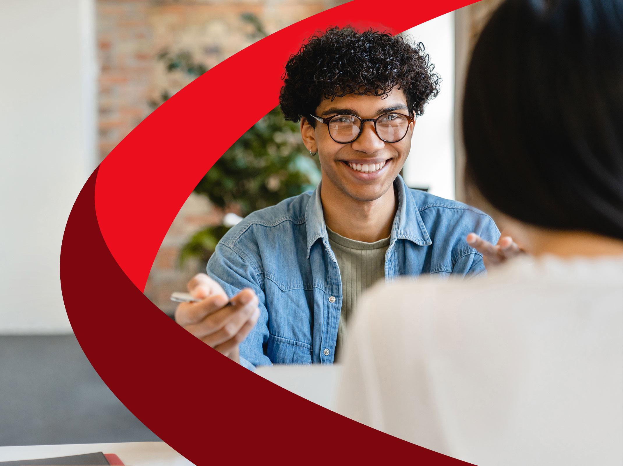 A business professional having a pleasant conversation with another person in an office setting.  They appear to have a good interpersonal relationship.